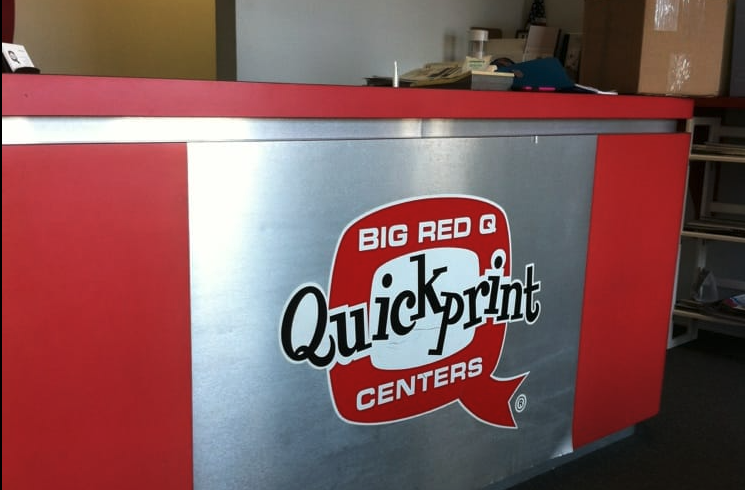 Counter at a print shop in Port Charlotte FL with Big Red Q Quickprint Centers logo