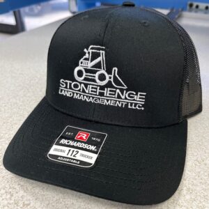 A black hat with Stonehenge Land Management LLC logo embroidered on it from a custom print shop in Port Charlotte Florida.